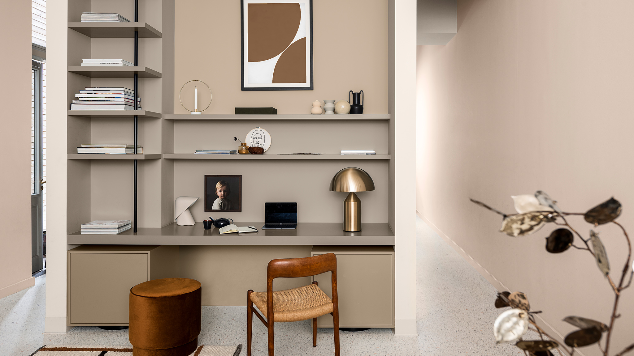 Leemkleurige boekenplanken met een houten stoel en een metalen lamp Leemkleurige boekenplanken met een houten stoel en een metalen lamp